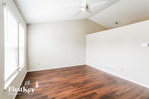 the spacious living room with wood flooring and a ceiling fan