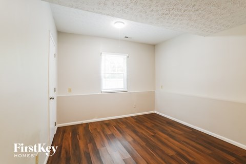 a bedroom with wood floors and white walls and a window
