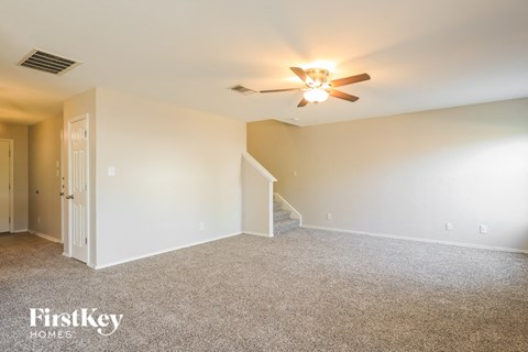 a spacious living room with carpet and a ceiling fan