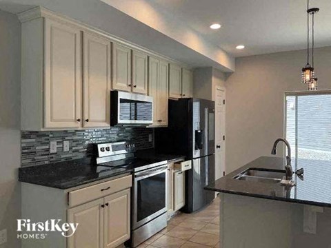 a kitchen with white cabinets and a black counter top