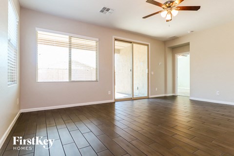 A spacious room with wooden floors and a ceiling fan.