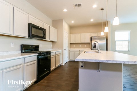 A kitchen with white cabinets and a black microwave.