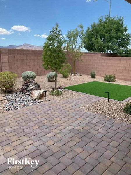 a backyard with a brick walkway and grass and a tree