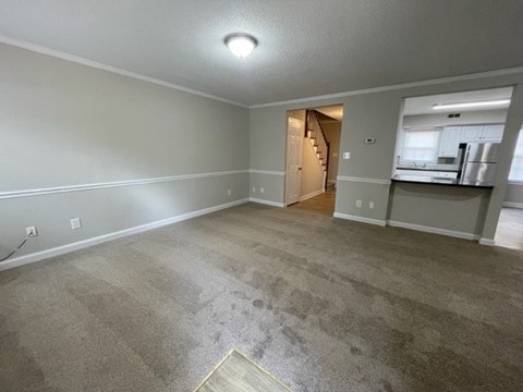 A spacious room with a carpeted floor and a doorway leading to another room.