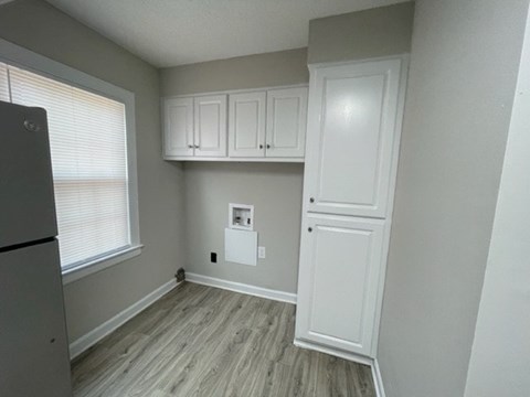 A kitchen with white cabinets and a refrigerator.