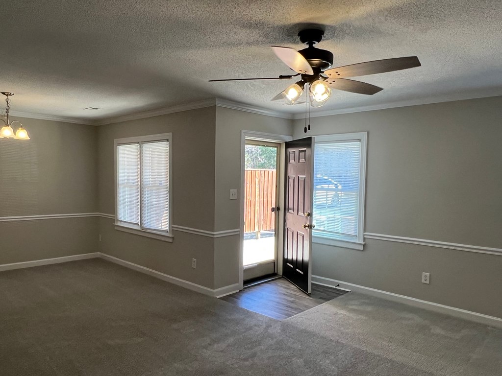 A room with a ceiling fan and a door leading outside.