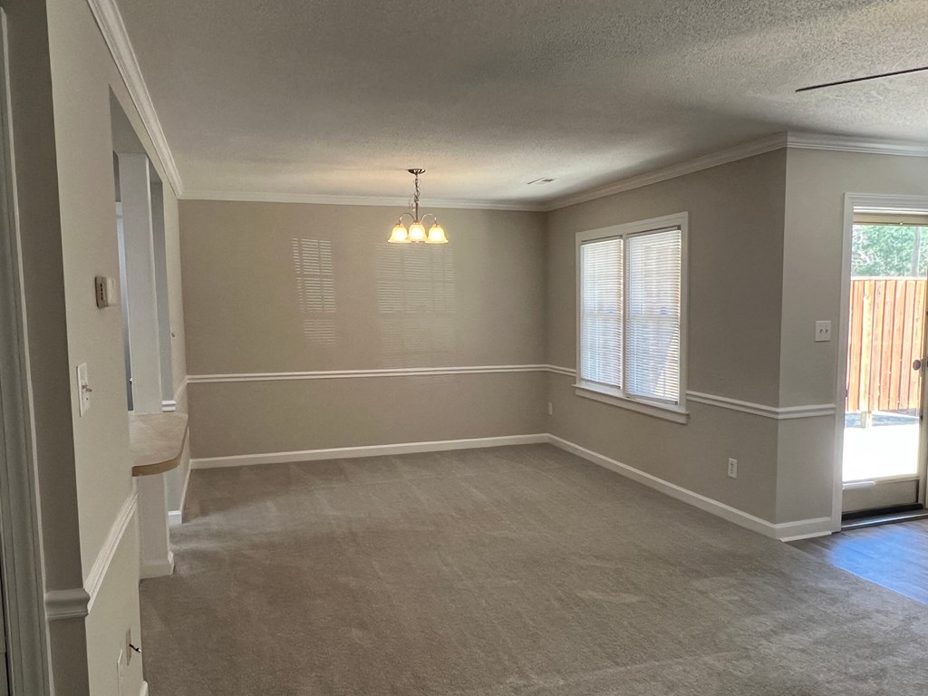 A room with a carpeted floor and a window with blinds.