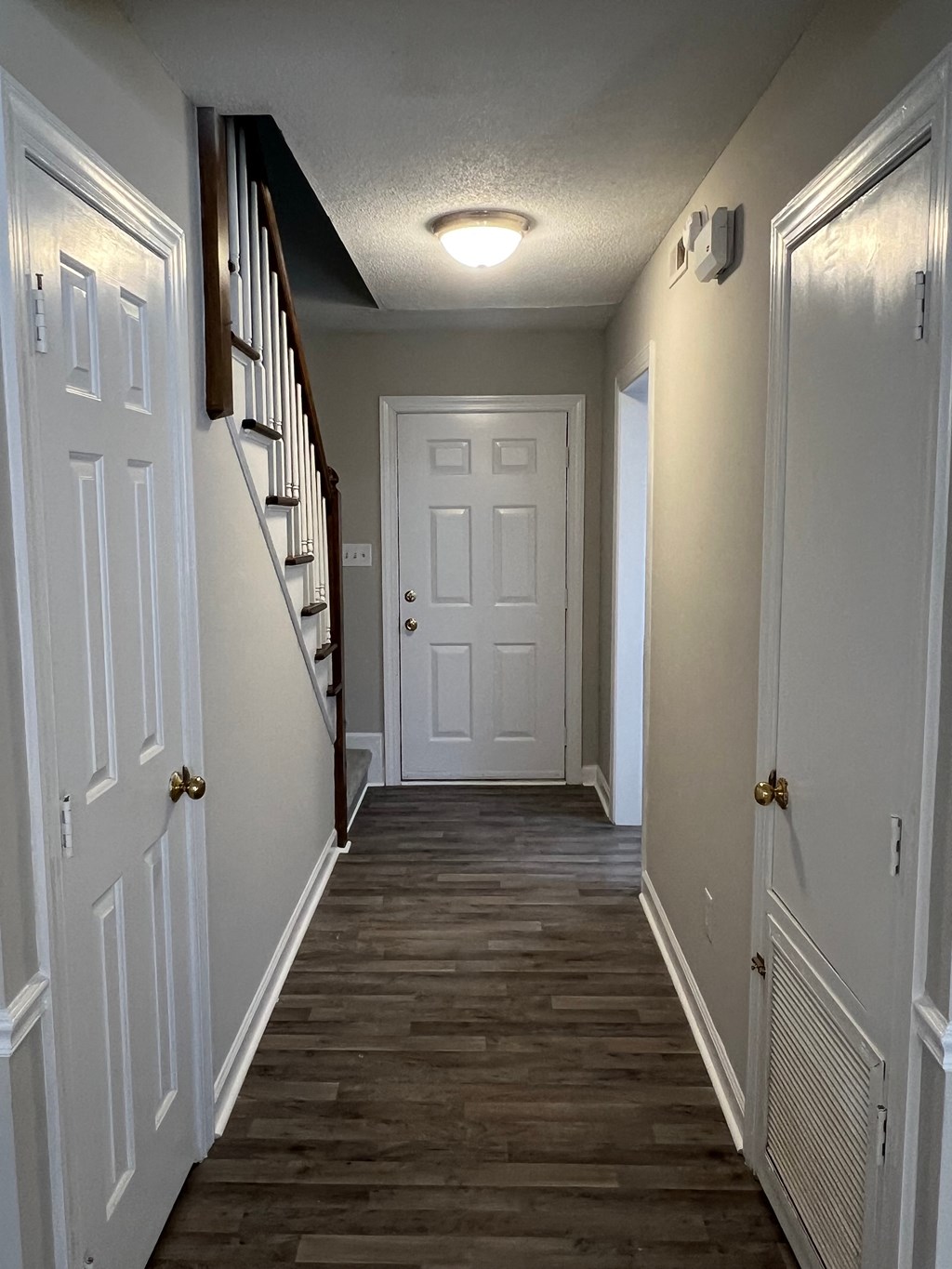A hallway with white doors and a wooden staircase.