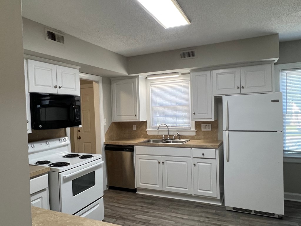 A kitchen with white cabinets and appliances.