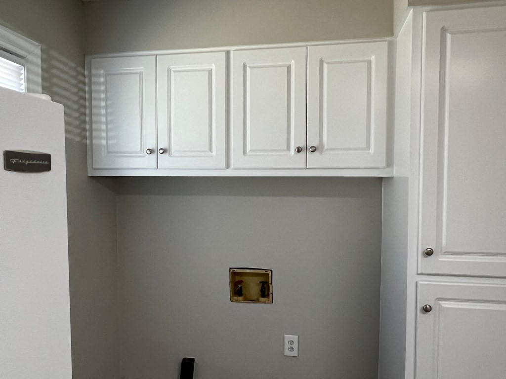 A kitchen with white cabinets and a fridge.