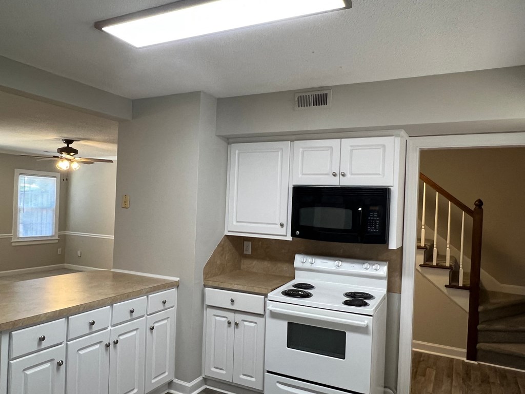 A kitchen with white appliances and cabinets.