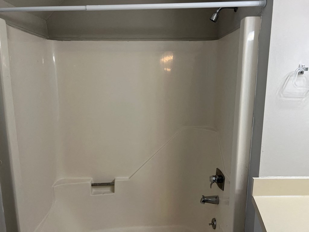 A white shower stall with a door and a handle.
