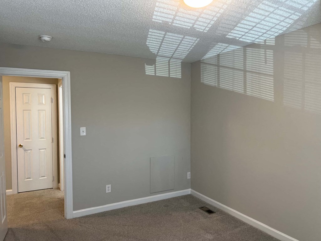 A room with a door and a window with blinds.