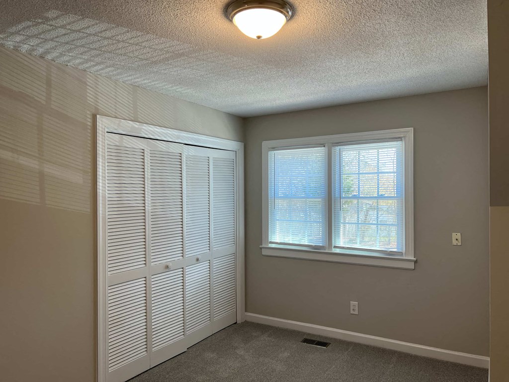 A room with a window and a door with blinds.