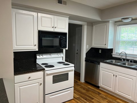 A kitchen with white cabinets and black countertops.