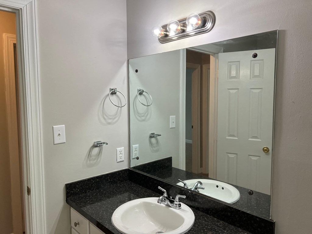 A bathroom with a sink, mirror, and towel rack.