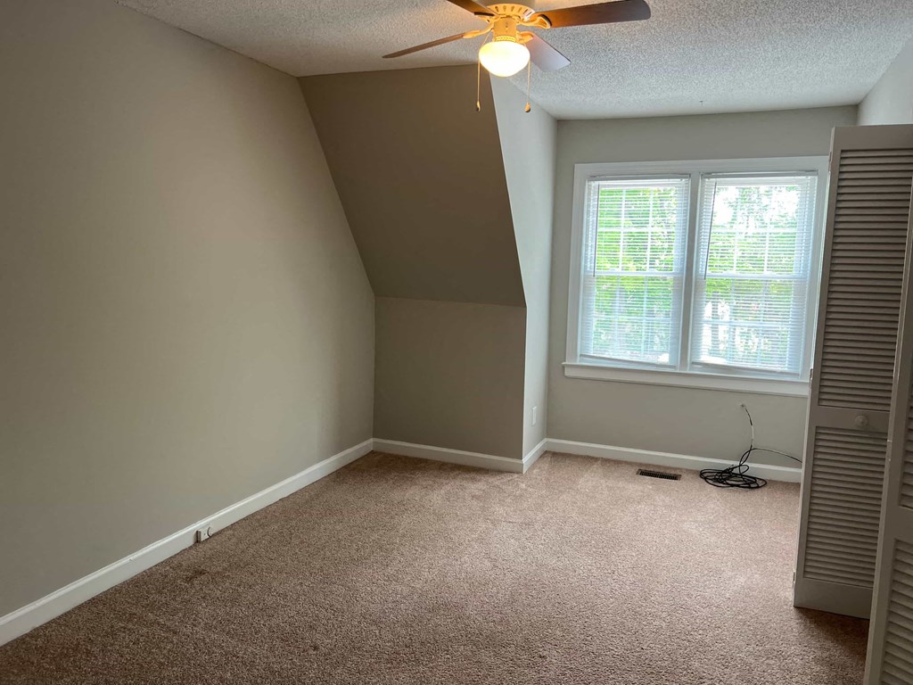 A room with a ceiling fan and a window.
