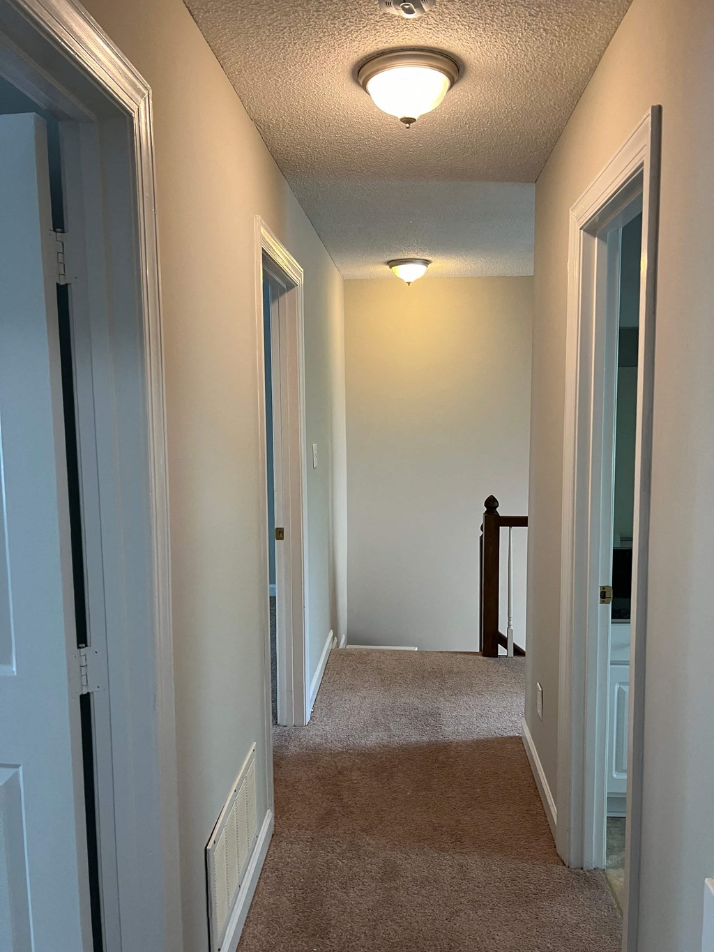A hallway with carpeted floors and white walls.