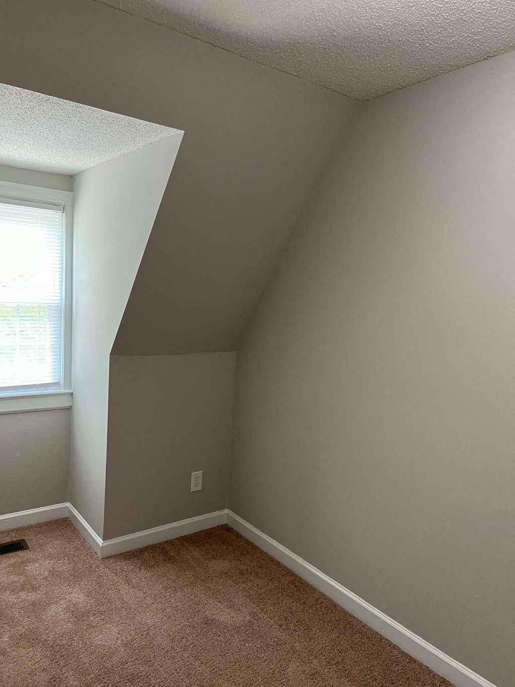 A room with a window and carpeted floor.