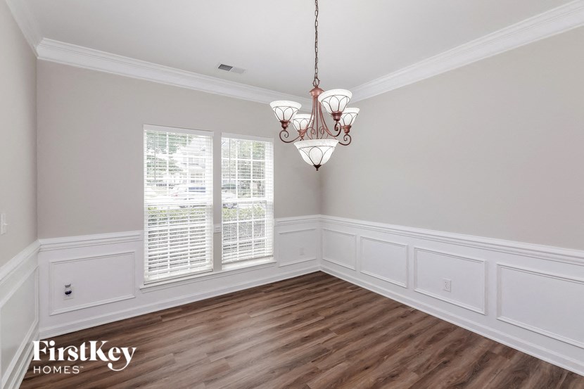 a dining room with white wainscoting and a chandelier
