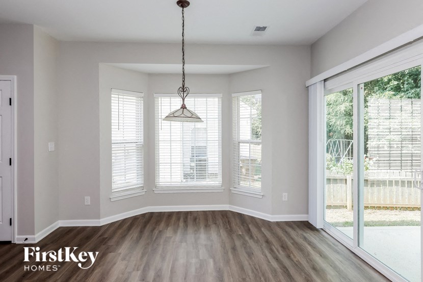 an empty living room with windows and a chandelier