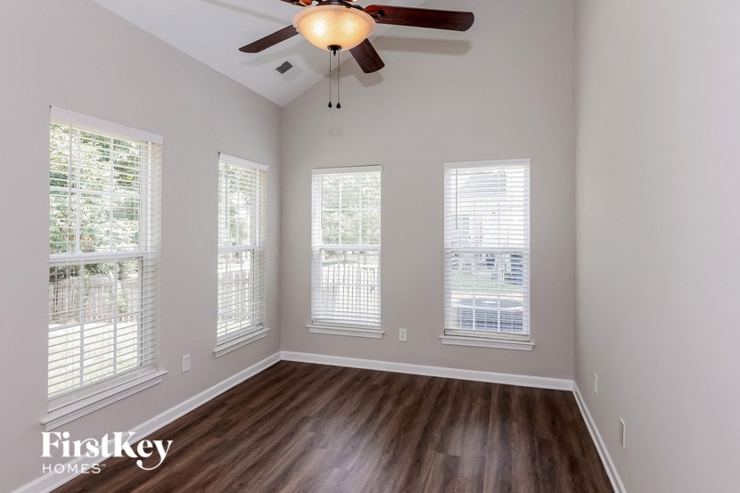 the living room of an empty home with a ceiling fan and windows
