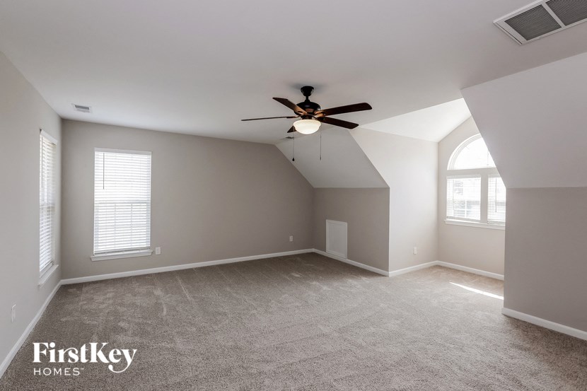 an empty living room with a ceiling fan and a window