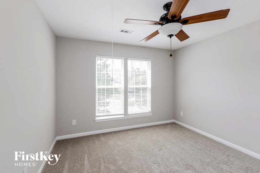 an empty room with a ceiling fan and a window