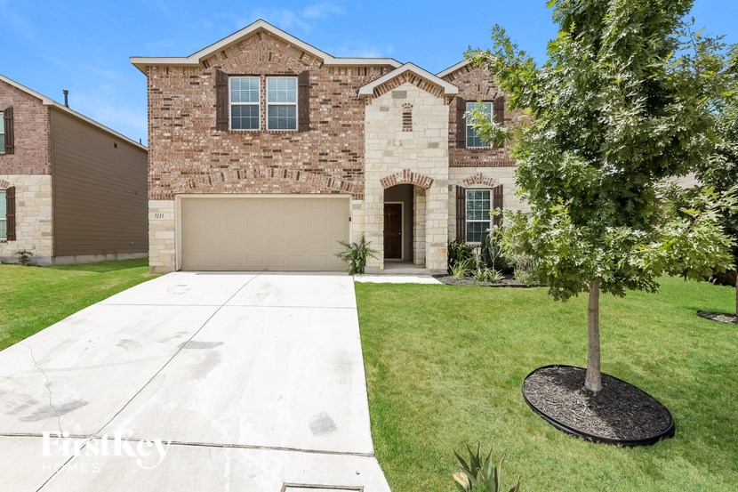 A house with a driveway and a tree in front.