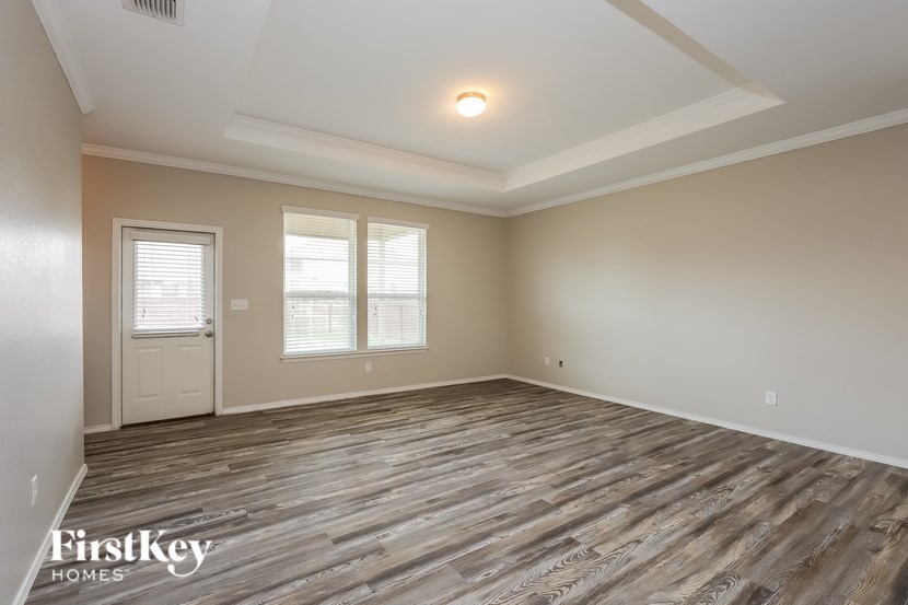 A room with wooden flooring and a window with blinds.