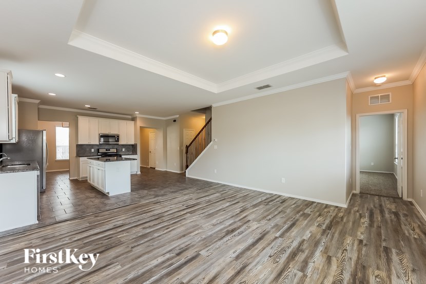 A spacious living room with wooden flooring and a staircase leading to another room.