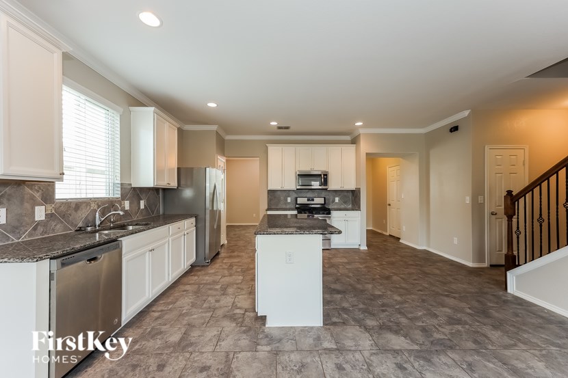A kitchen with a refrigerator, sink, and microwave.