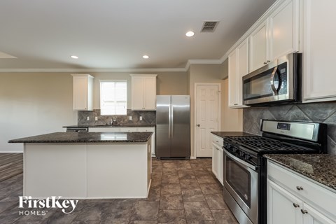 A kitchen with a black counter top and a stainless steel refrigerator.