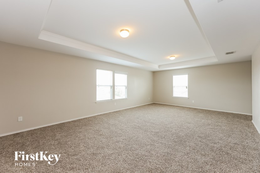 A spacious room with carpeted floor and two windows.