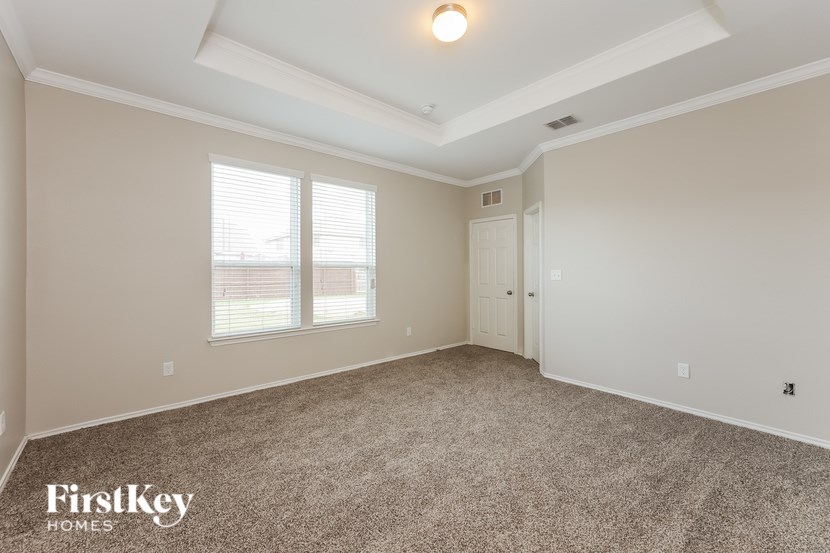 A spacious room with a carpeted floor and a window with blinds.