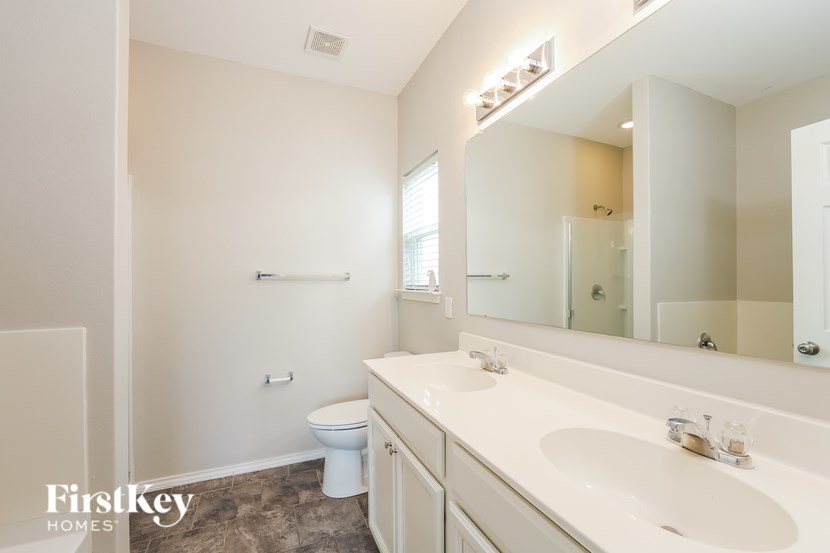 A bathroom with a toilet, sink, and mirror.