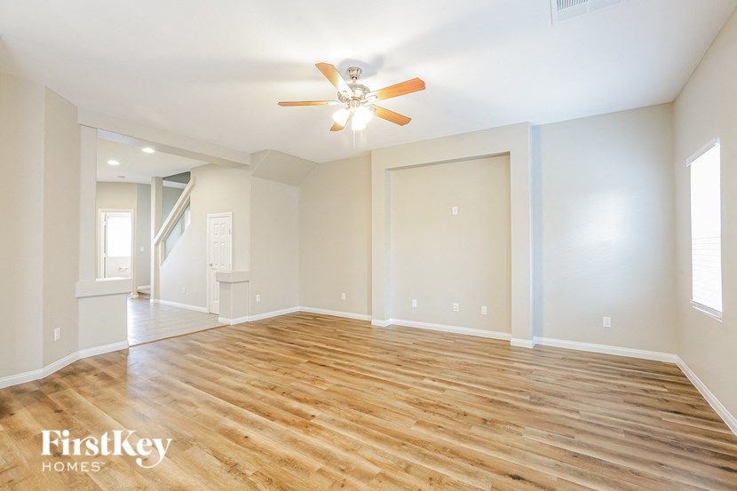 A spacious room with wooden floors and a ceiling fan.