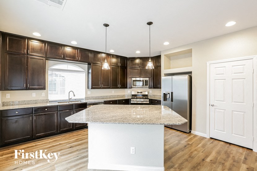 A kitchen with a granite countertop and wooden cabinets.