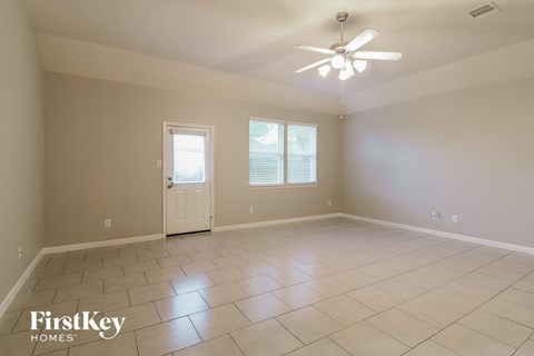 A spacious room with a ceiling fan and two windows.