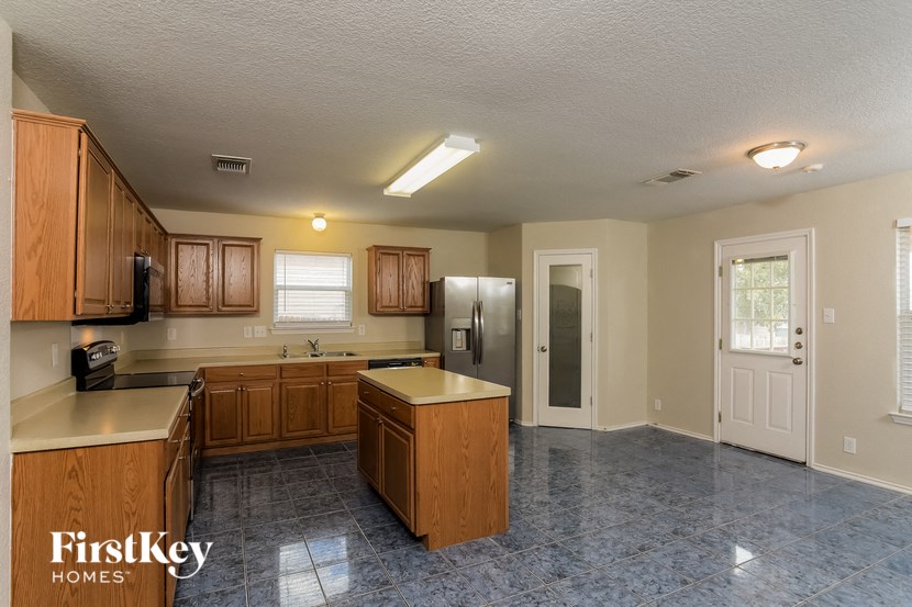 an empty kitchen with wooden cabinets and a stainless steel refrigerator