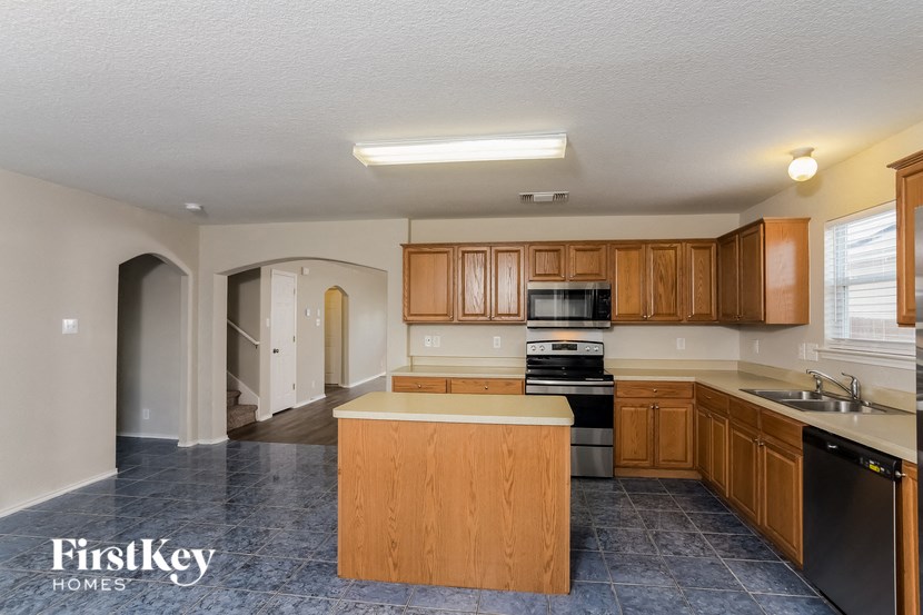 an empty kitchen with wood cabinets and black appliances