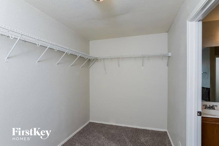 a closet in a white room with white rods on the wall