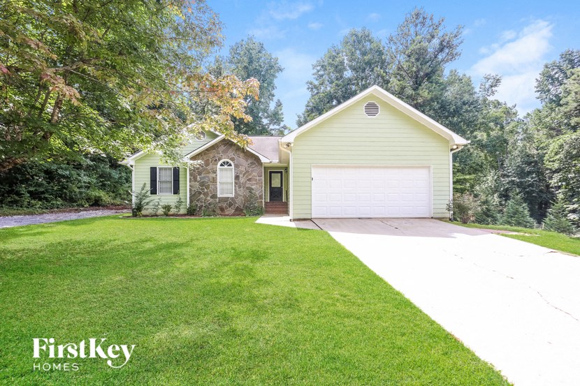 a yellow house with a white driveway and a garage door