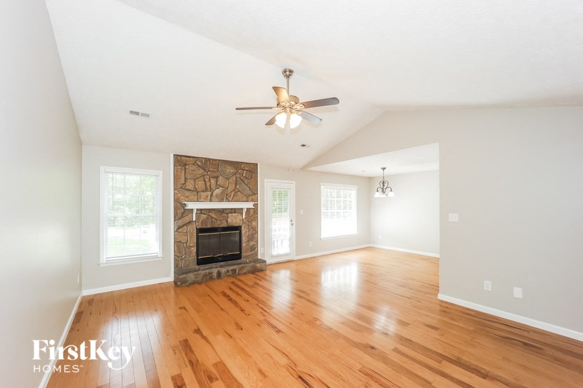 a living room with a fireplace and wooden floors and a ceiling fan