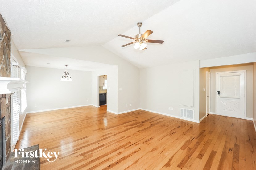 the living room and dining room with hardwood floors and a ceiling fan