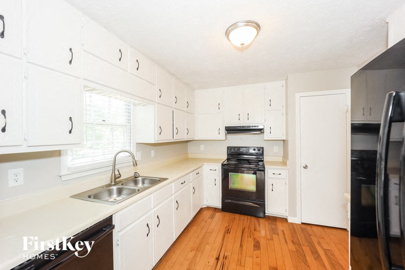 a kitchen with white cabinets and black appliances