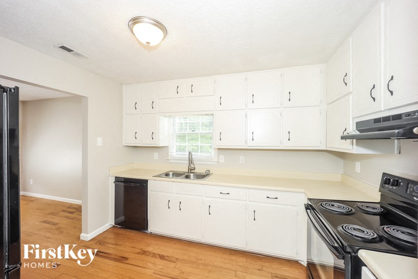 a white kitchen with white cabinets and a black stove top oven