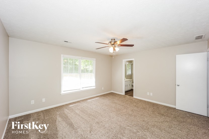the spacious living room with carpet and ceiling fan