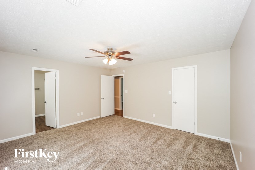 a spacious living room with carpet and a ceiling fan