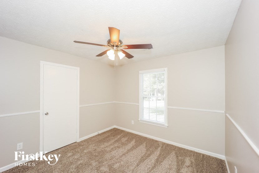 a bedroom with white walls and a ceiling fan